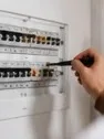 Revizní technik kontroluje jističe v rozvaděči